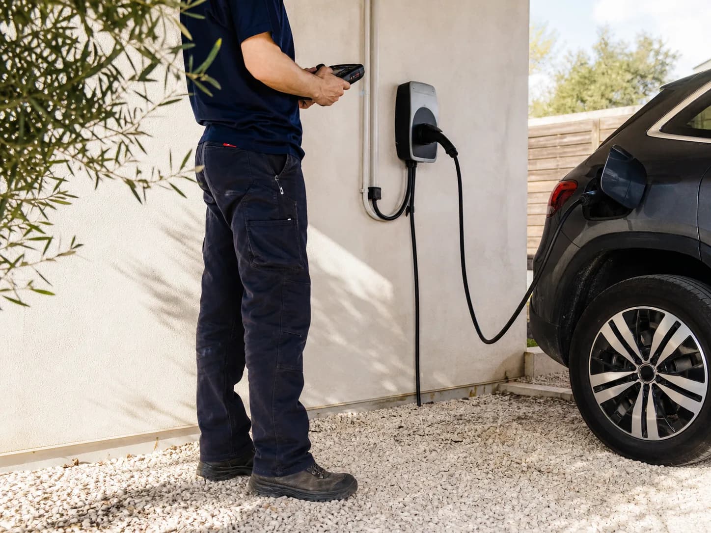 Technicien contrôlant une borne de recharge installée dans un garage résidentiel