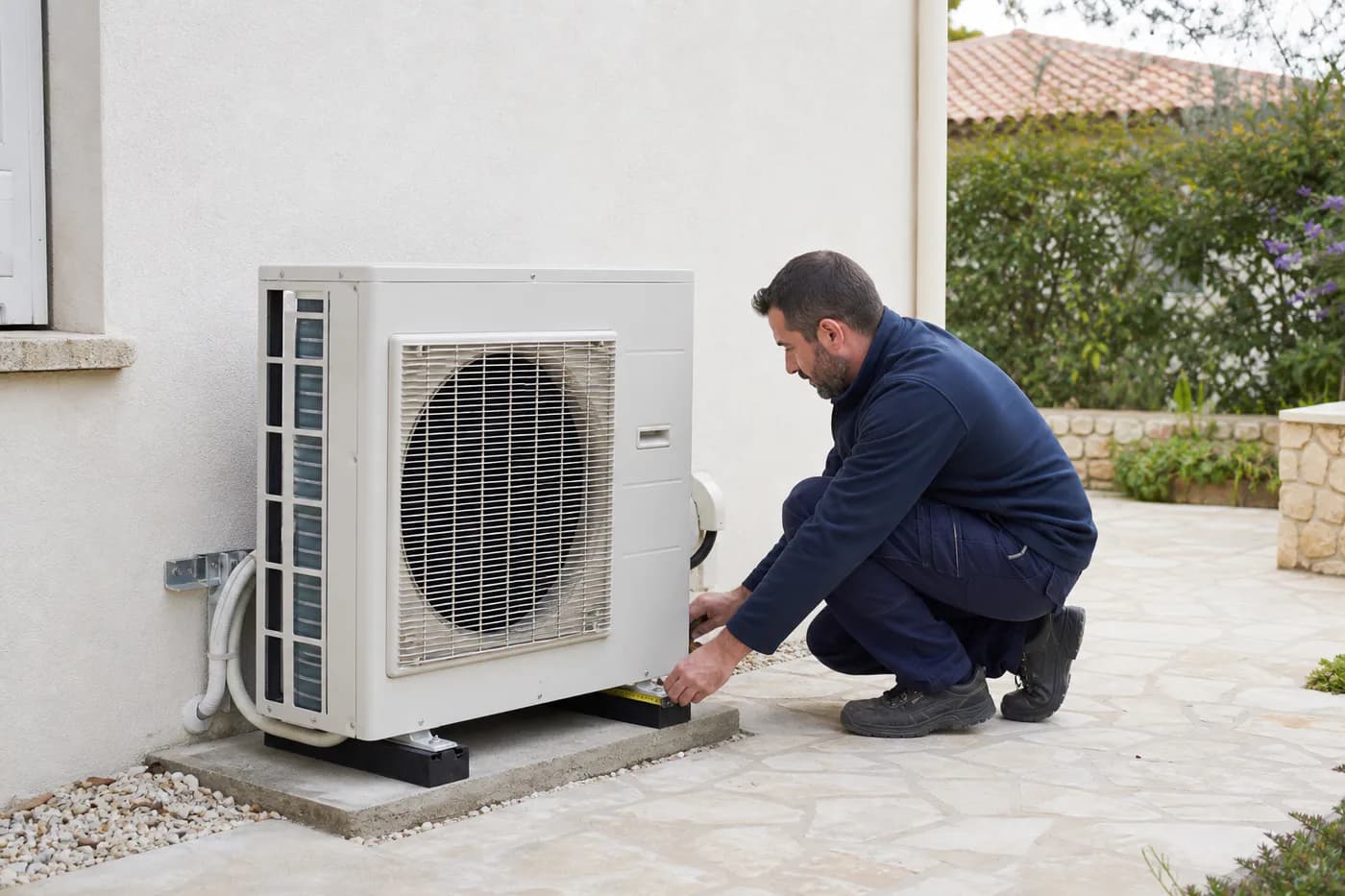Technicien contrôlant l’implantation d’une unité extérieure de climatisation près d’une maison